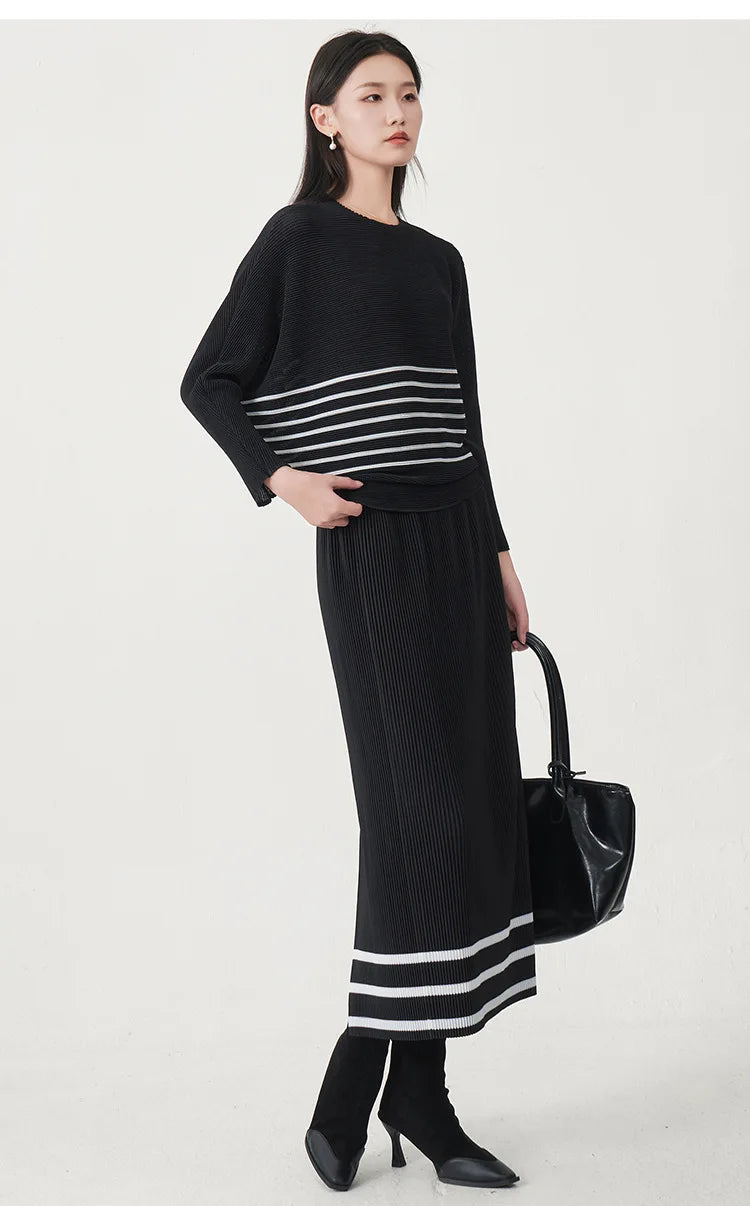 A trending women's clothing item for 2026: a matching black batwing-sleeved striped T-shirt and straight-cut skirt set by Miyake