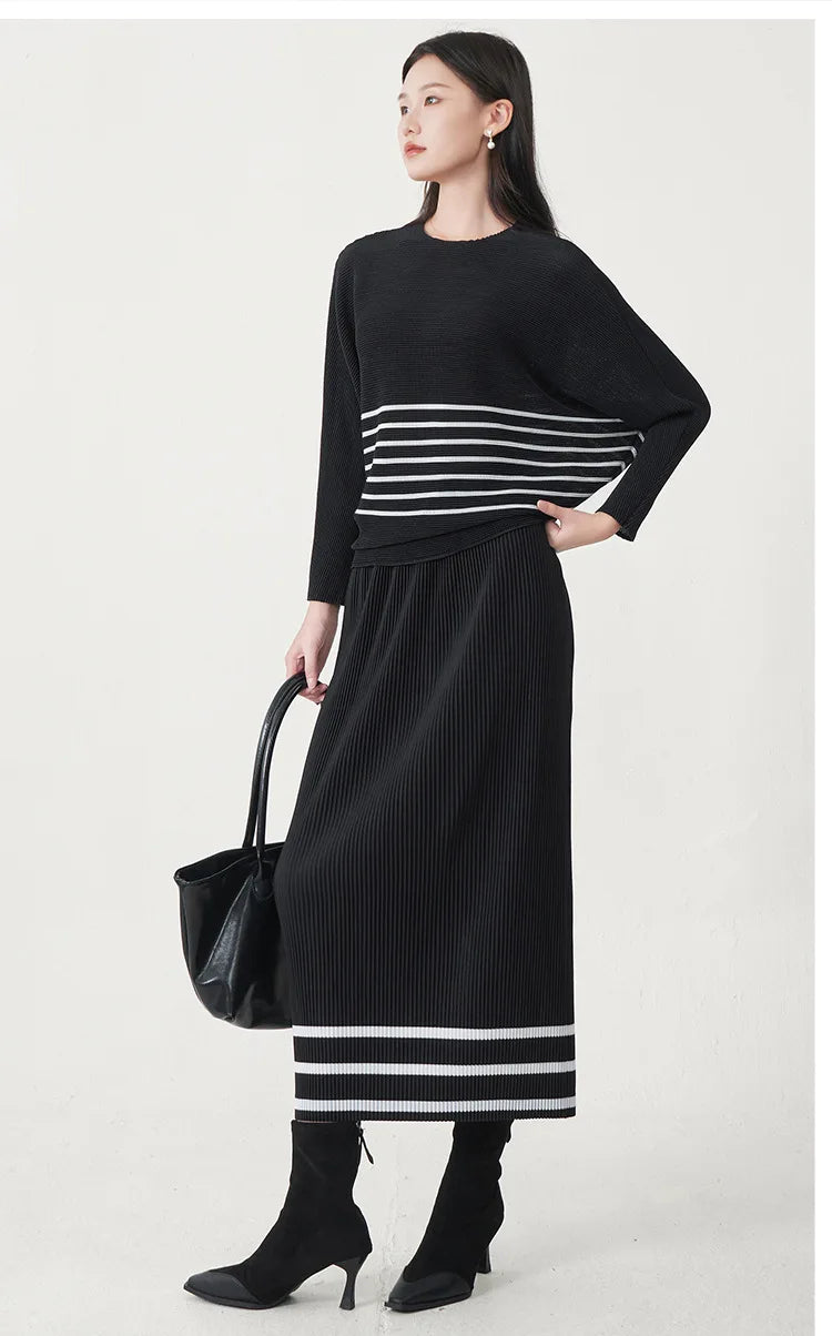 A trending women's clothing item for 2026: a matching black batwing-sleeved striped T-shirt and straight-cut skirt set by Miyake