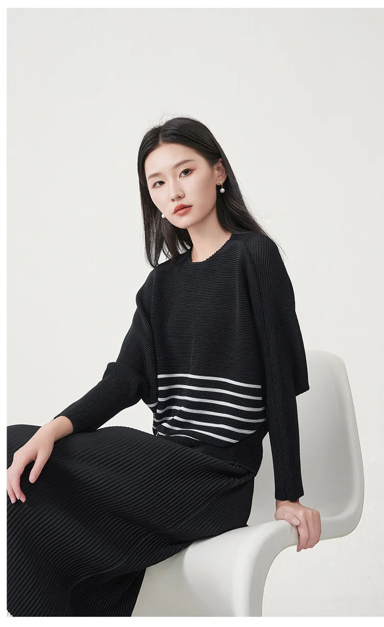 A trending women's clothing item for 2026: a matching black batwing-sleeved striped T-shirt and straight-cut skirt set by Miyake